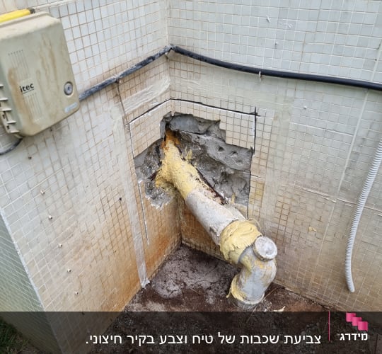 צינור מתכת עם בידוד צהוב בקיר אריחים
